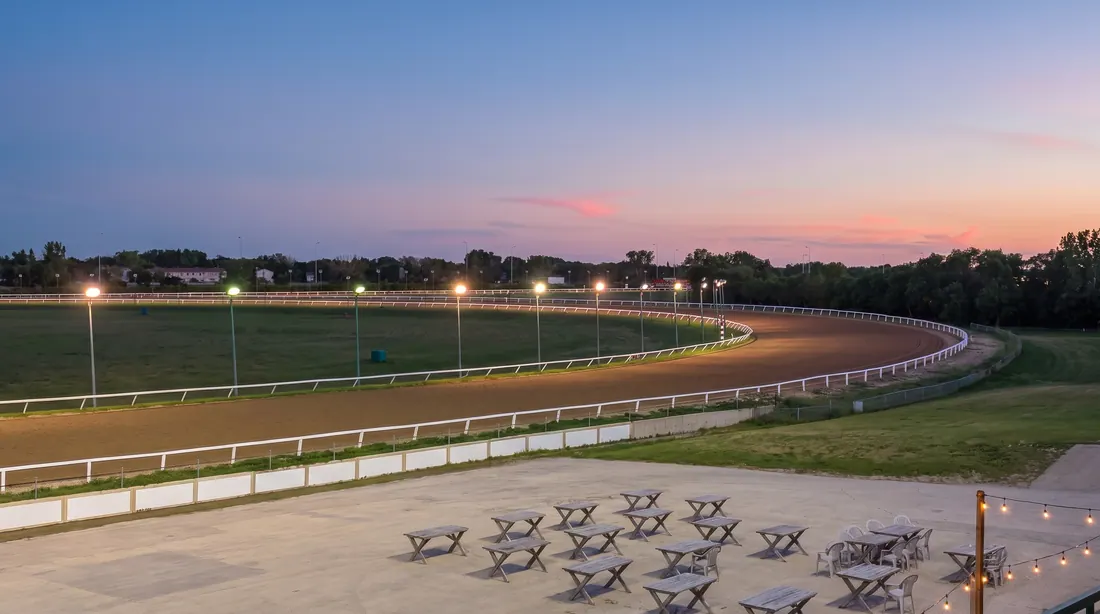 Empty picnic tables on the Assiniboia Downs apron at dusk