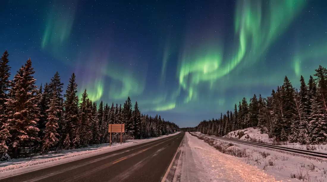 Northern highway and rail line under green aurora